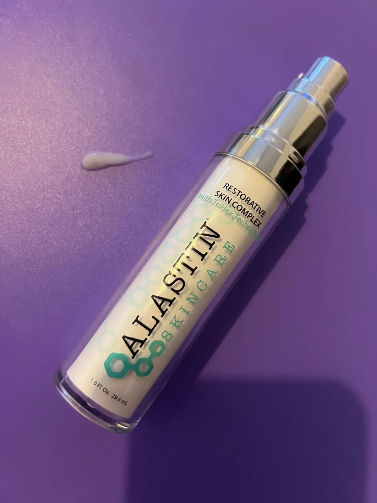 ALASTIN Restorative Skin Complex bottle with a small product swatch on a purple background
