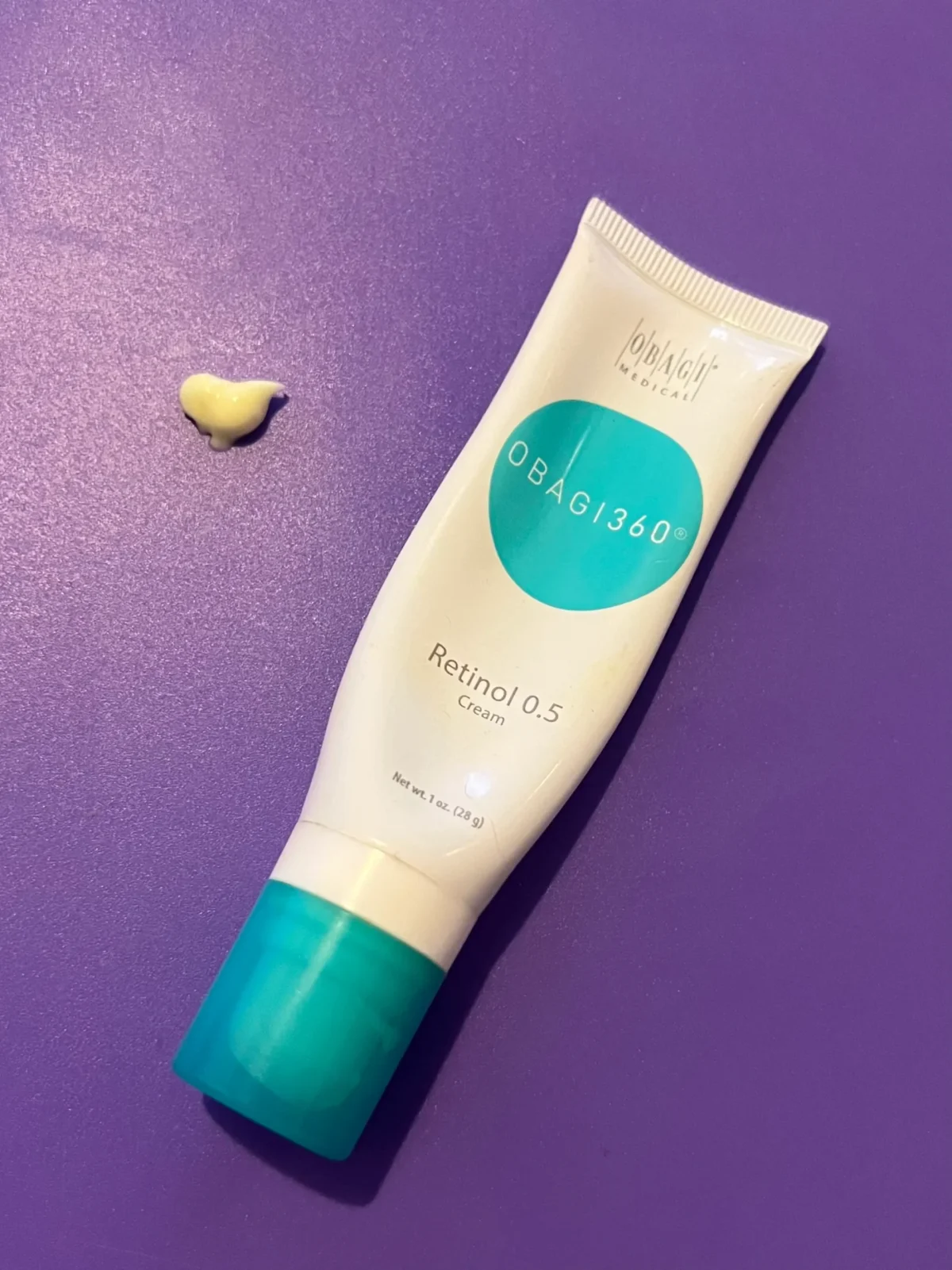 Obagi360 Retinol 0.5 Cream tube with pale-yellow cream texture on a purple background