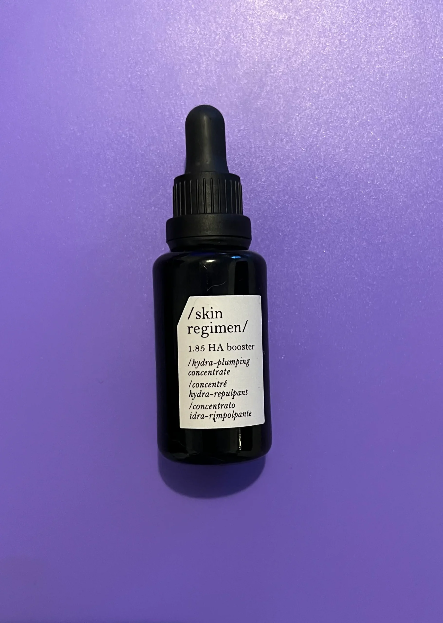 Skin Regimen 1.85 HA Booster dropper bottle on a purple background