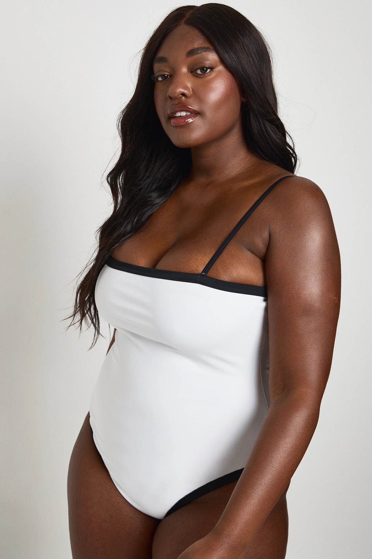 Model wearing the Boohoo white square-neck one-piece swimsuit with black trim