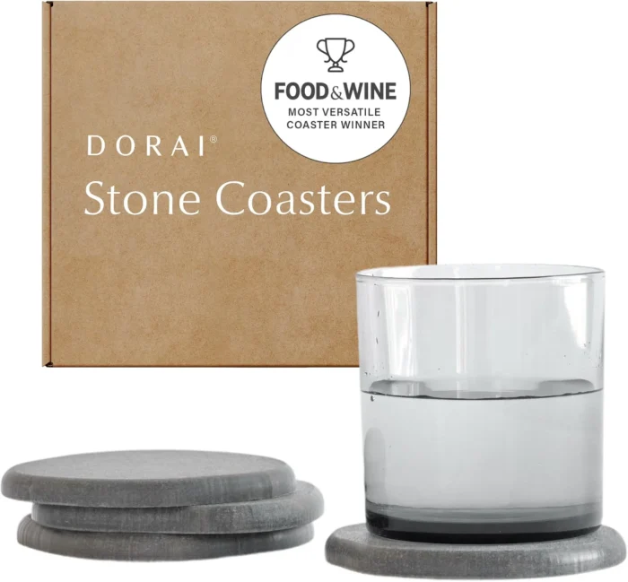 Four rounded Dorai Stone Coasters beside their box, with a glass on one coaster