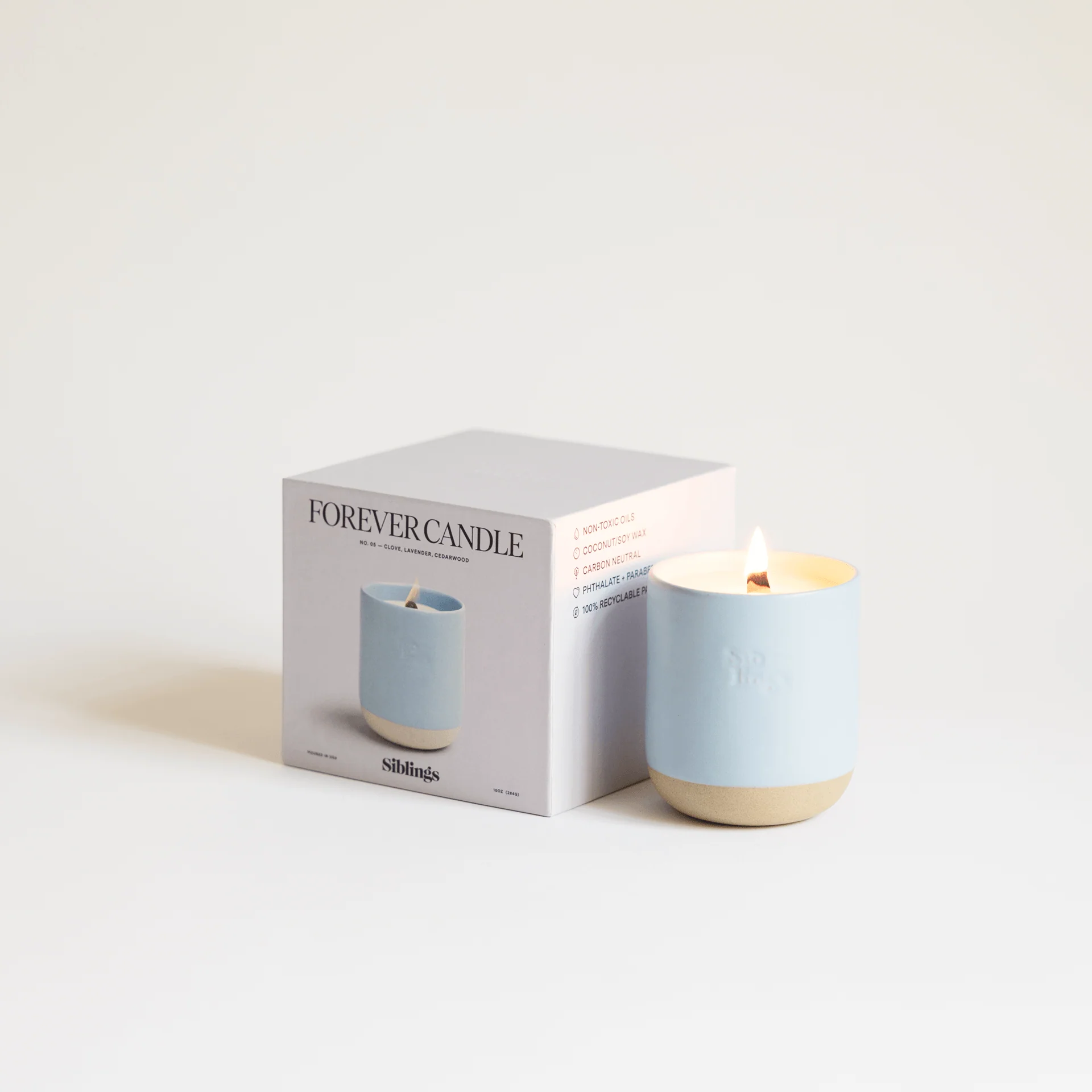 Pale blue Siblings Forever Candle beside its box.