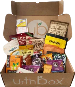 Open UrthBox box filled with assorted packaged snacks.
