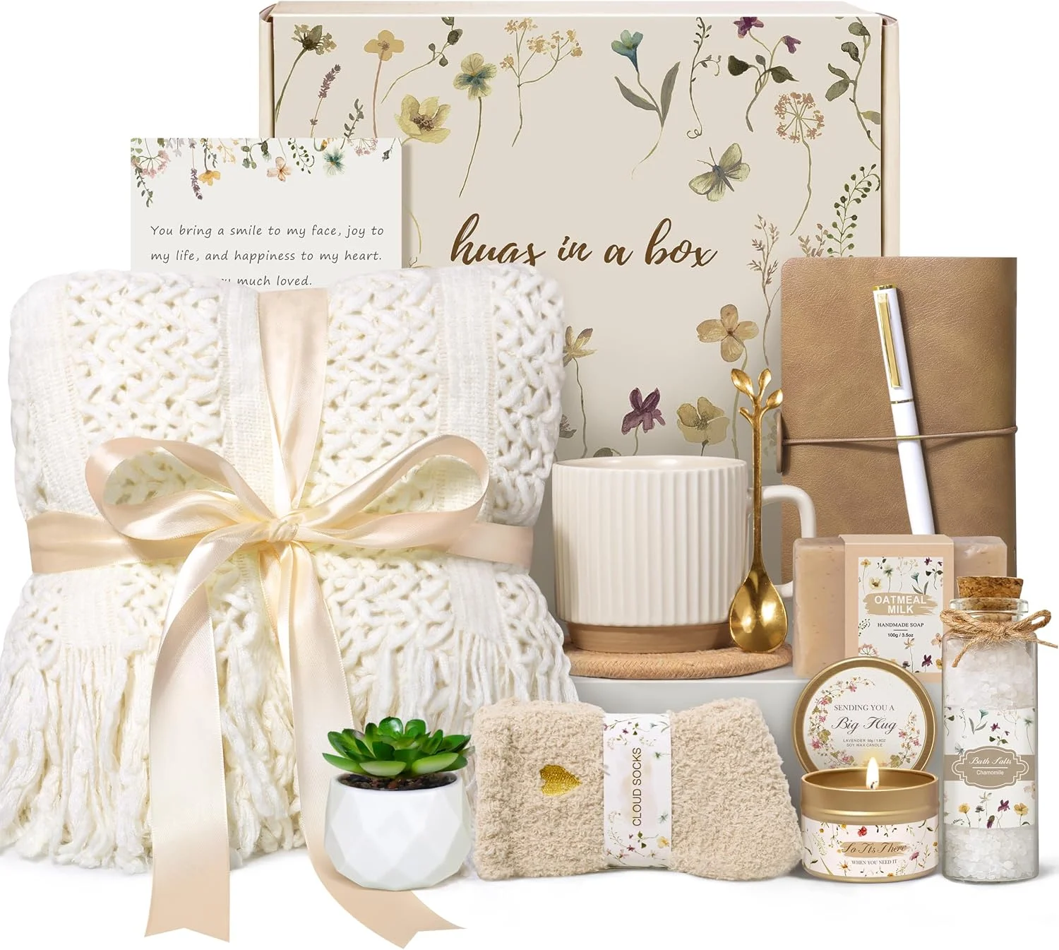 Cream blanket, mug, socks, candle and bath items arranged with a floral gift box.